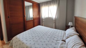 Een slaapkamer met een groot bed, een houten garderobe en een spiegel.