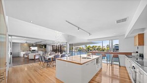 Une cuisine moderne dotée d’un grand îlot central, de planchers en bois et offrant une vue sur l’extérieur.