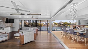 Un vaste espace de vie doté d’un plancher en bois, d’un canapé, d’une table à manger pouvant accueillir six personnes et d’une grande fenêtre donnant sur une marina.
