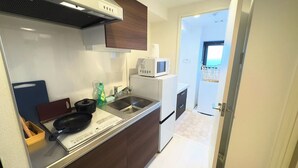 A compact kitchen with a microwave, sink, and a small refrigerator. - Rakuyado Sanno (Osaka)
