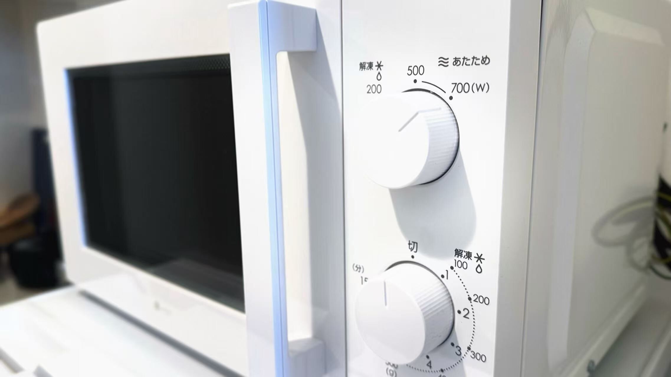 A microwave with a control panel featuring a dial and buttons, including a power button and a timer.