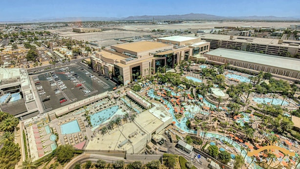 A large hotel with multiple swimming pools, a parking lot, and a view of distant mountains. - MGM Signature-Jacuzzi Pool & LazyRiver  Studio (Las Vegas)