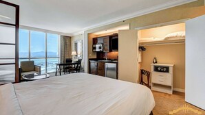 A hotel room with a large bed, a dining area, a kitchenette, and a view of the ocean. - MGM Signature-Jacuzzi Pool & LazyRiver  Studio (Las Vegas)