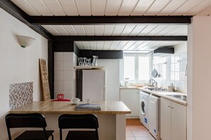 A compact kitchen with a wooden island, a washing machine, and a window providing natural light. - A 5 passi dalla Fontana di Trevi – Loft romano del XVII secolo! (Rome)