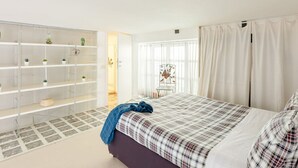 A bedroom with a bed, a shelving unit with plants, and a chair. - A 5 passi dalla Fontana di Trevi – Loft romano del XVII secolo! (Rome)