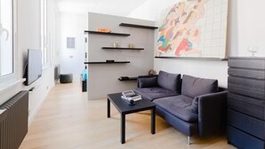 Una sala de estar moderna con un sofá, una mesa de centro y una obra de arte en la pared.