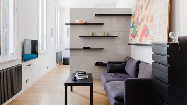 Una sala de estar moderna con un sofá, una mesa de centro y estanterías empotradas.