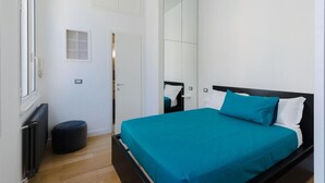 Un dormitorio con cama, espejo, radiador y puerta.