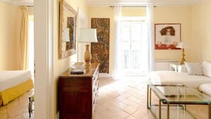 Une chambre d’hôtel avec un lit, une table basse en verre, une commode et un tableau au mur.