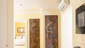 Un couloir avec des portes à motifs, une commode en bois et un sol carrelé.