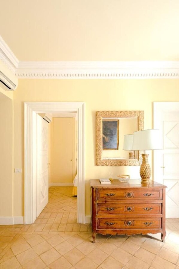 A room with a wooden dresser, a framed picture, and a lamp.