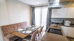 Een compacte keuken met een eethoek, een bank en een raam met gordijnen.