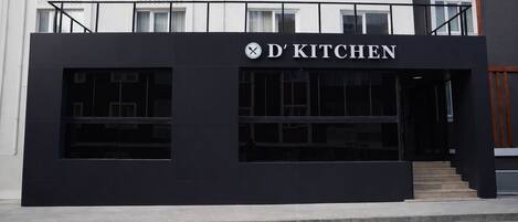 A modern building with a sign reading 'D' KITCHEN' and large windows.