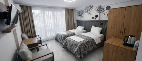 A hotel room with two beds, a desk, a TV, and a wardrobe.
