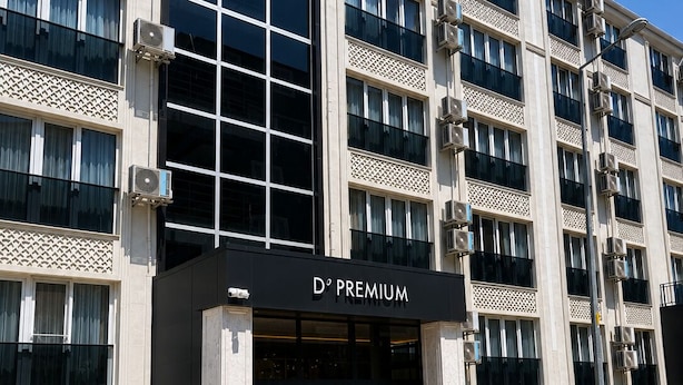 Ein mehrstöckiges Hotel mit moderner Fassade, Klimaanlagen und einem auffälligen Eingang mit der Beschriftung 'D PREMIUM'.