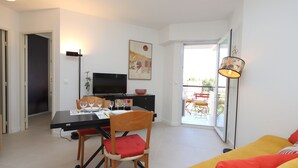 A modern living room with a dining area, a flat-screen TV, and a sofa.