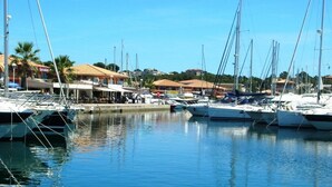 A marina with several boats docked, a clear sky, and buildings in the background.