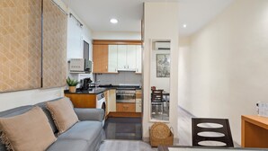 A compact living space with a kitchenette, a dining area, and a seating area with a sofa and cushions.