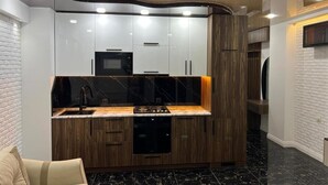 Een moderne keuken met witte kasten, een zwart aanrecht en een wand bekleed met hout.