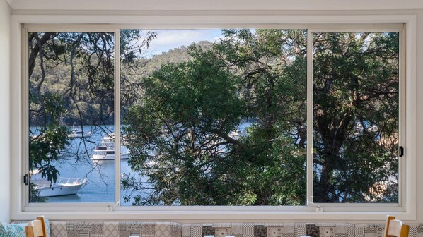 Una ventana con vistas a un lago, barcos y árboles.