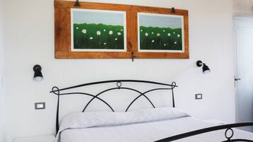 Una camera da letto con una struttura letto in metallo, una testiera in legno, una panca e due quadri appesi al muro.