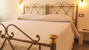Una cama con estructura metálica y cabecera de madera, una mesita de noche y lámparas fijadas a la pared.