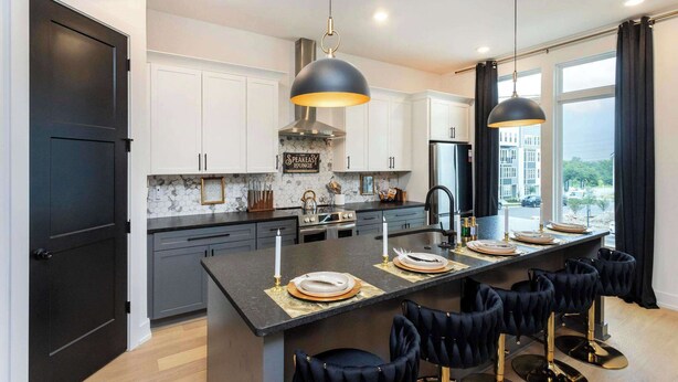 A modern kitchen with dark cabinetry, a marble backsplash, and a central island with bar stools.