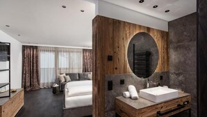 Habitación de hotel moderna con una cama grande, una tocador de madera con espejo y un amplio ventanal con cortinas.