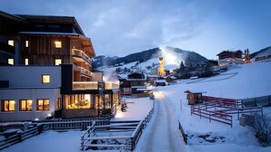 Un pueblo cubierto de nieve con edificios modernos, una iglesia y un telesilla.