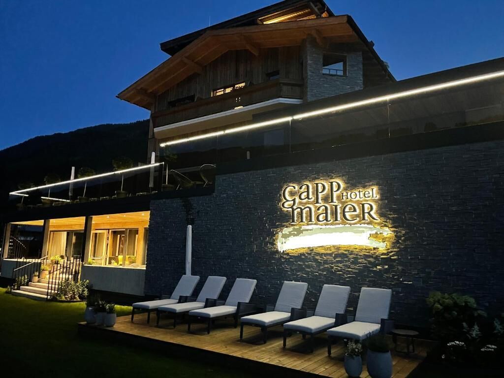 A hotel exterior with a prominent sign, outdoor seating area, and a staircase leading to an upper level.