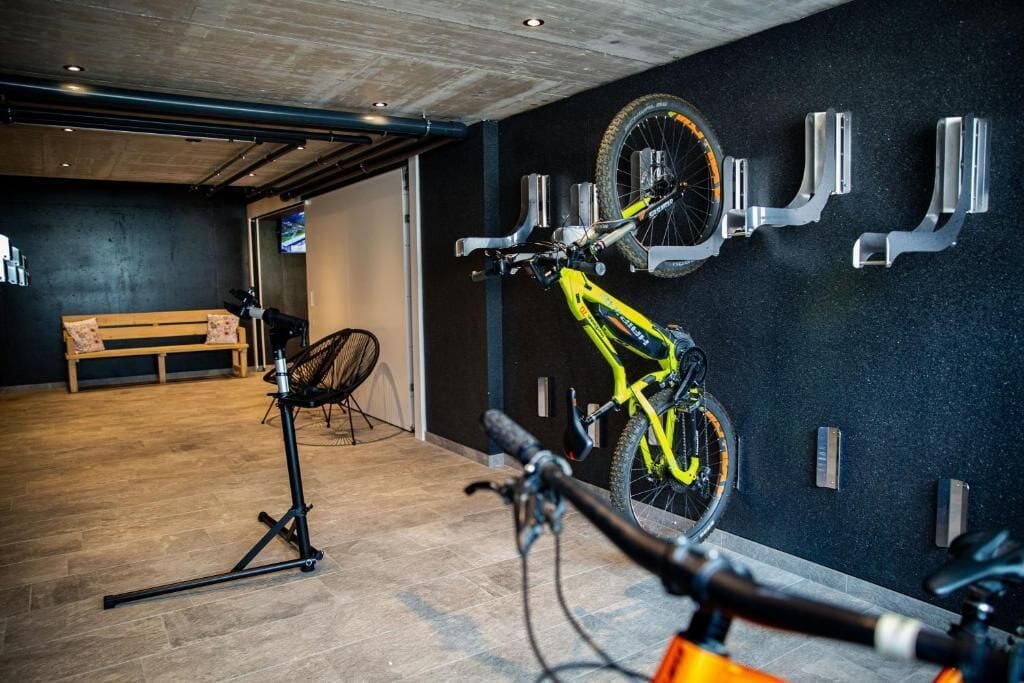 Una habitación con un banco de madera, una bicicleta colgada en la pared y un trípode.