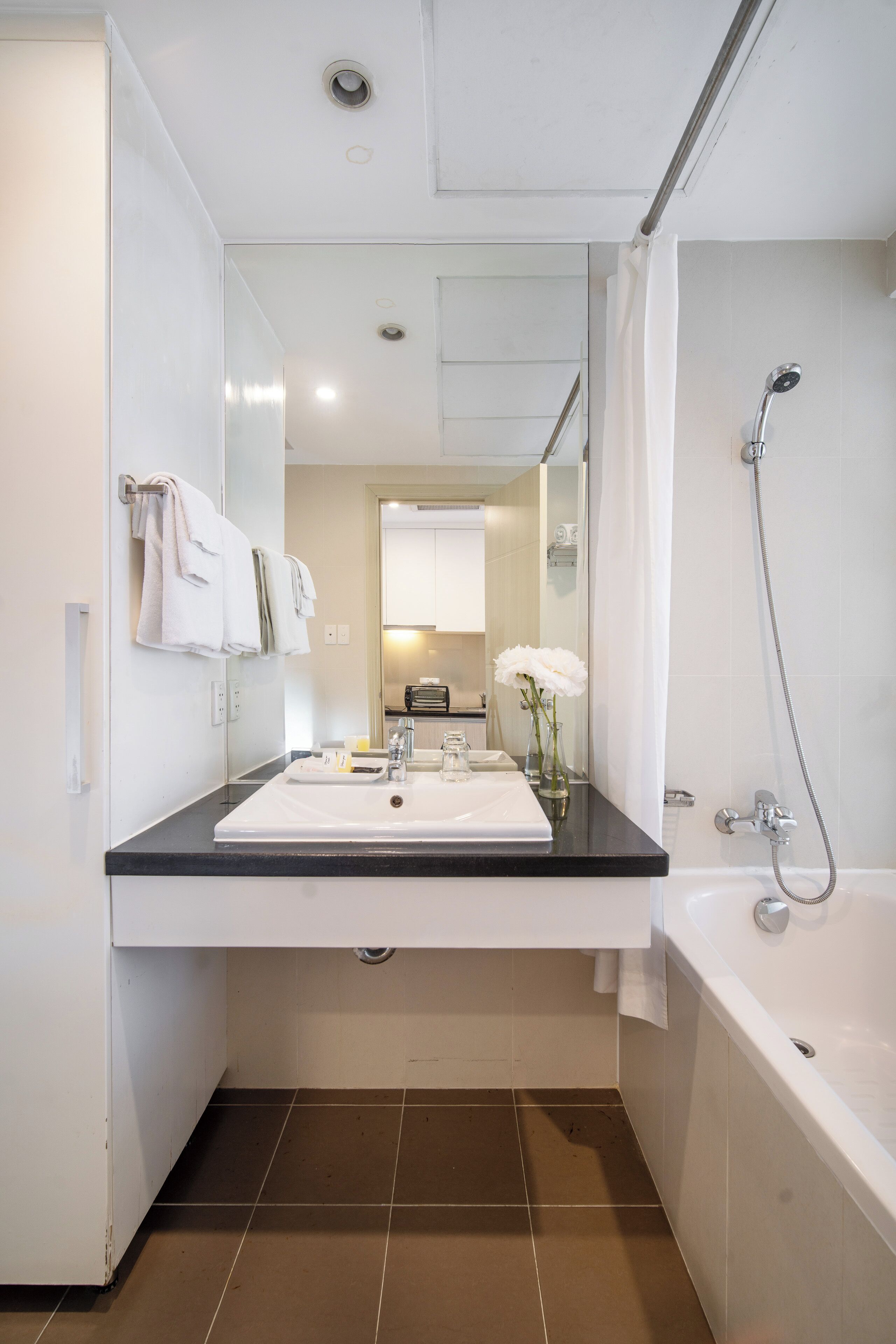 A modern bathroom with a sink, mirror, and bathtub.
