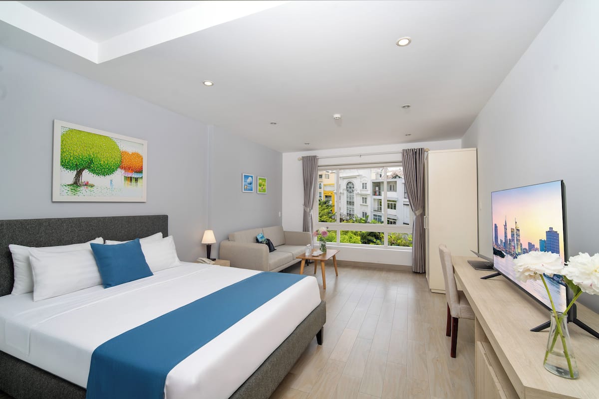 Una habitación de hotel moderna con una cama grande, un escritorio, un televisor y una ventana con vistas a la ciudad.