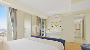 Una habitación de hotel moderna con una cama grande, un espacio de descanso y vistas a la ciudad.