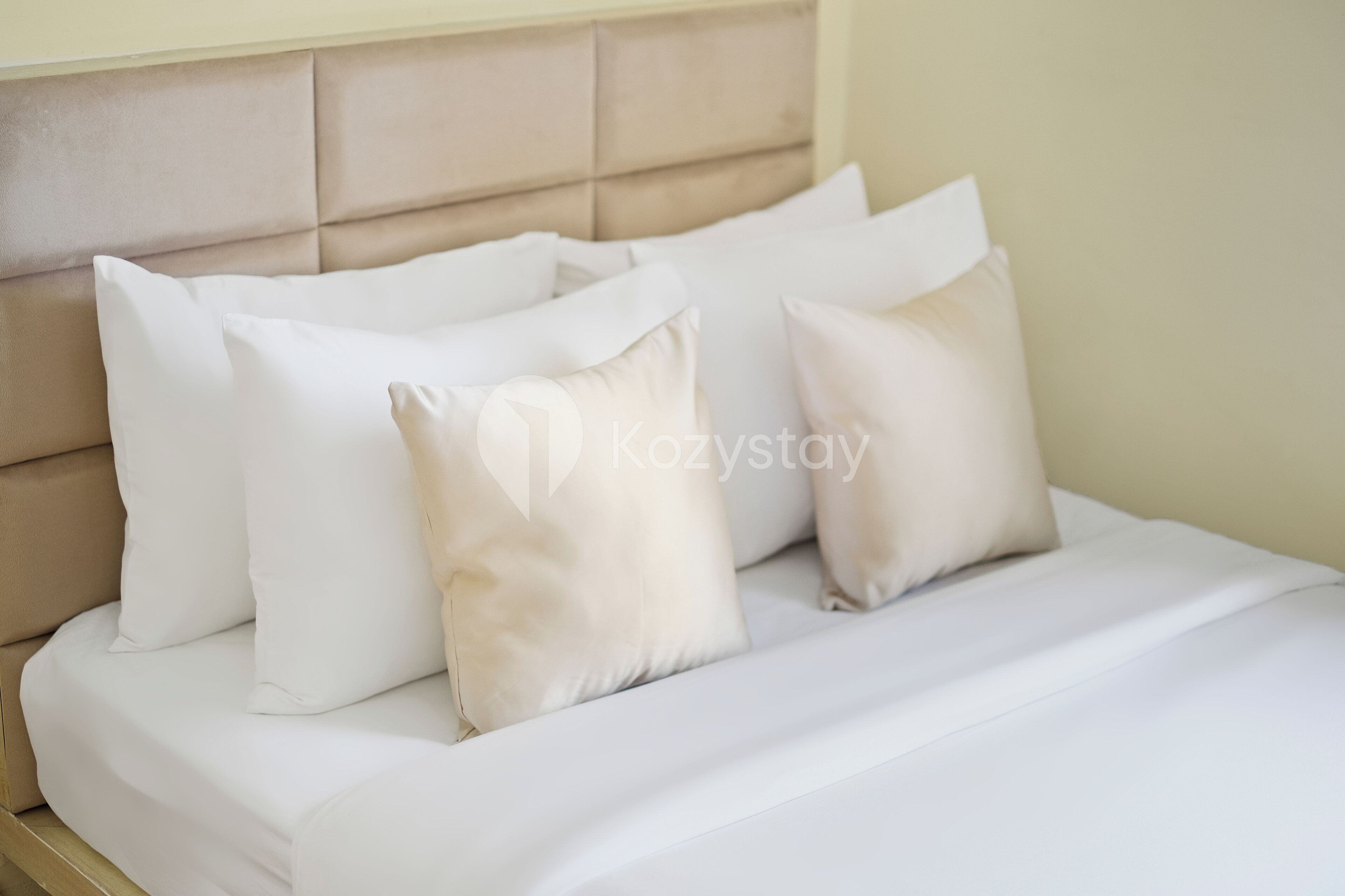 Un lit avec une tête de lit beige et du linge de lit blanc.
