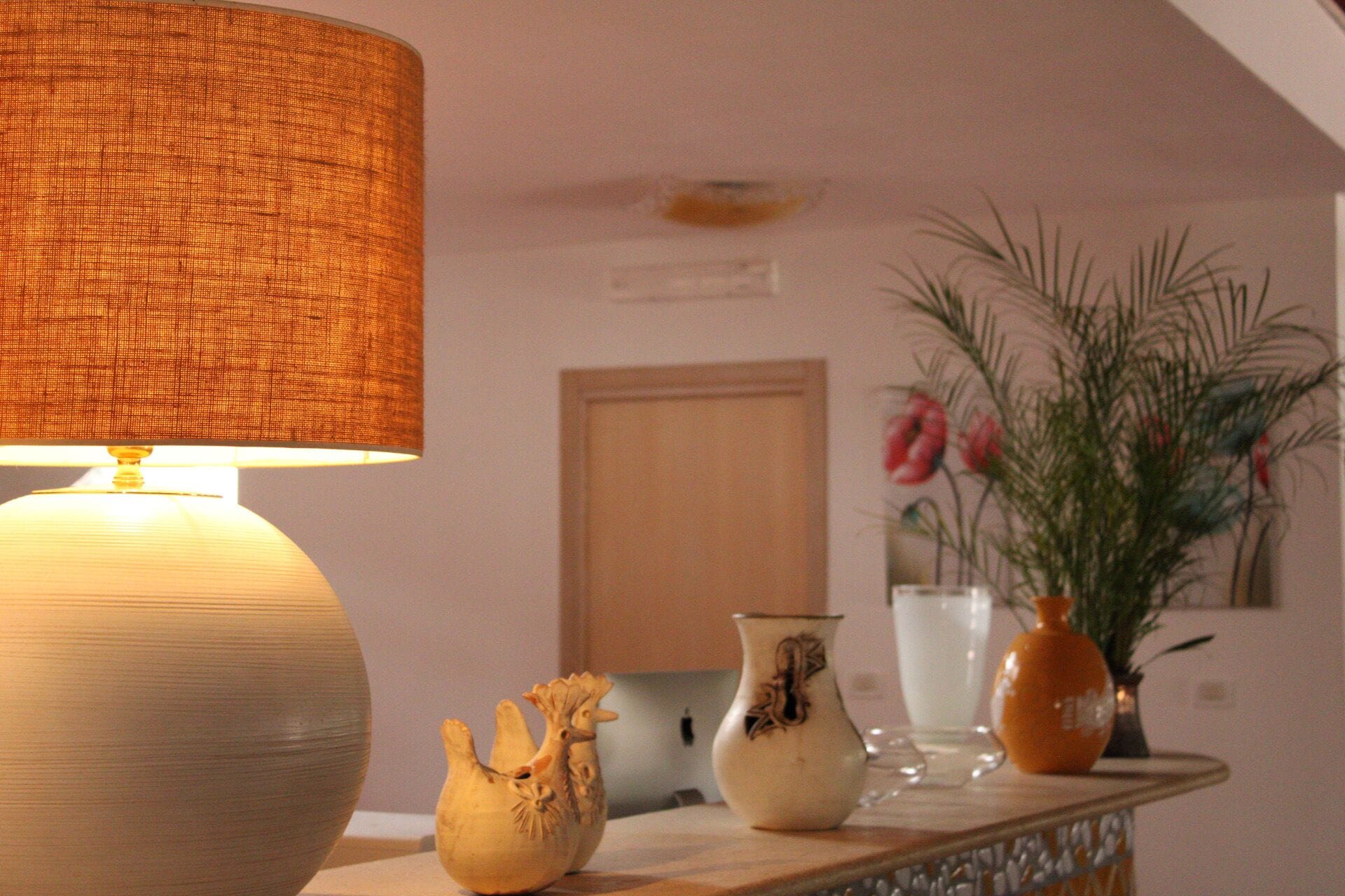 A room with a lamp, a vase with flowers, and a decorative bowl on a wooden table.