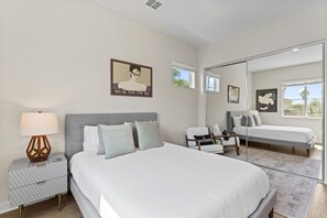 Une chambre moderne avec un grand lit, des tables de chevet, une chaise et un miroir.