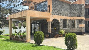 A two-story house with a balcony, a stone facade, and a well-maintained lawn. - Lux Suites Lakeview Mansion Nakuru (Nakuru)