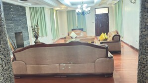 A spacious living room with a large sofa, a chandelier, and a decorative wall. - Lux Suites Lakeview Mansion Nakuru (Nakuru)