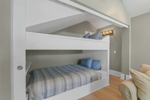Un letto a castello con una lampada sopra, un divano e un pavimento in legno.