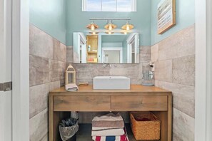 Un bagno con un mobile bagno in legno, uno specchio grande e un lampadario sopra lo specchio.