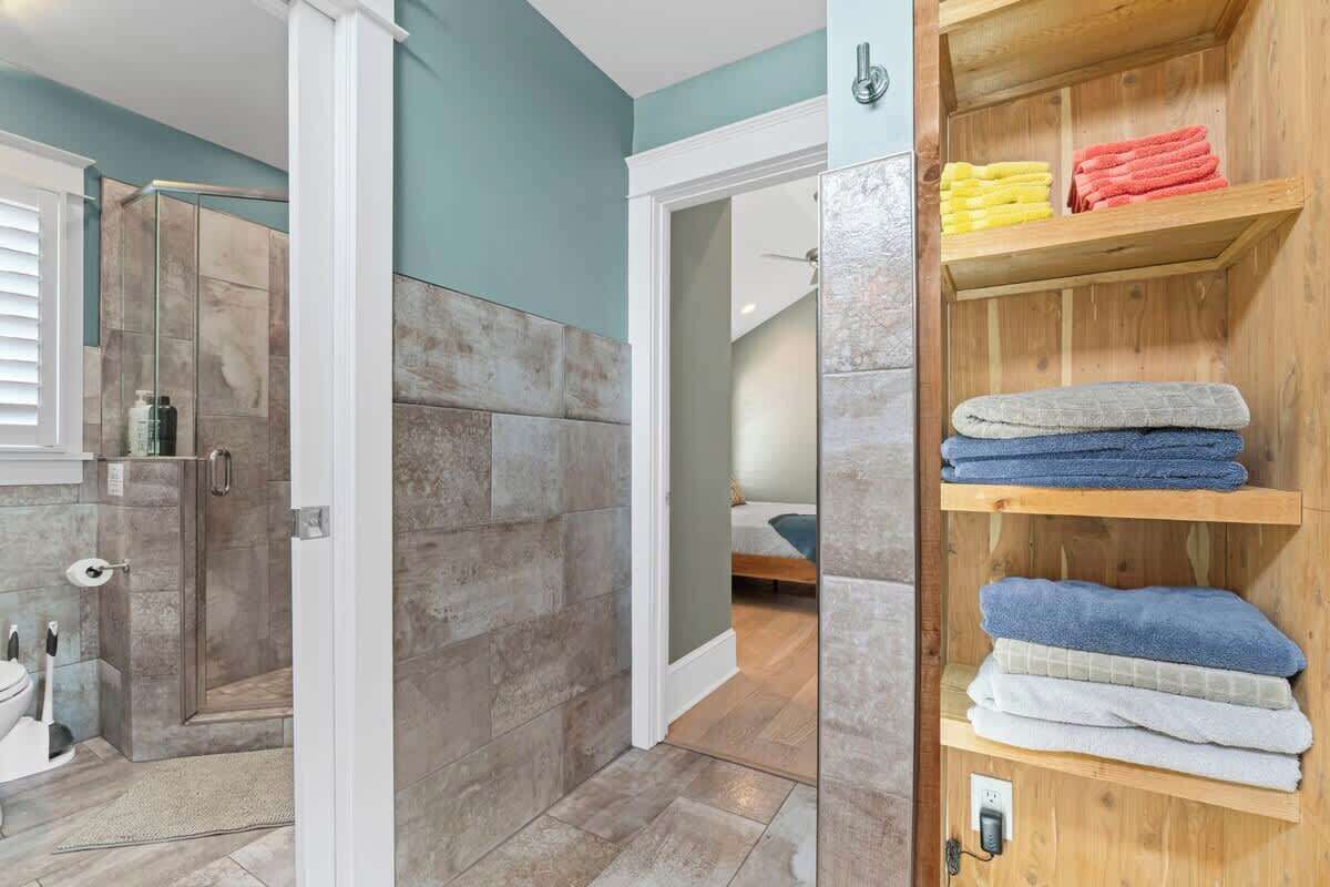 Ein Badezimmer mit Dusche, Toilette und einem Handtuchhalter mit gefalteten Handtüchern.