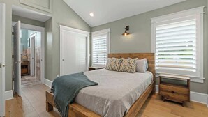Un dormitorio con una cama de madera, una mesita de noche, un banco y una lámpara de pared.