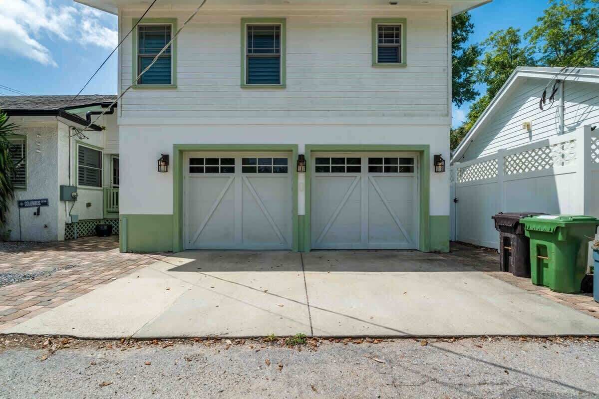 Ein zweistöckiges Haus mit Garage, Auffahrt und weißem Zaun.