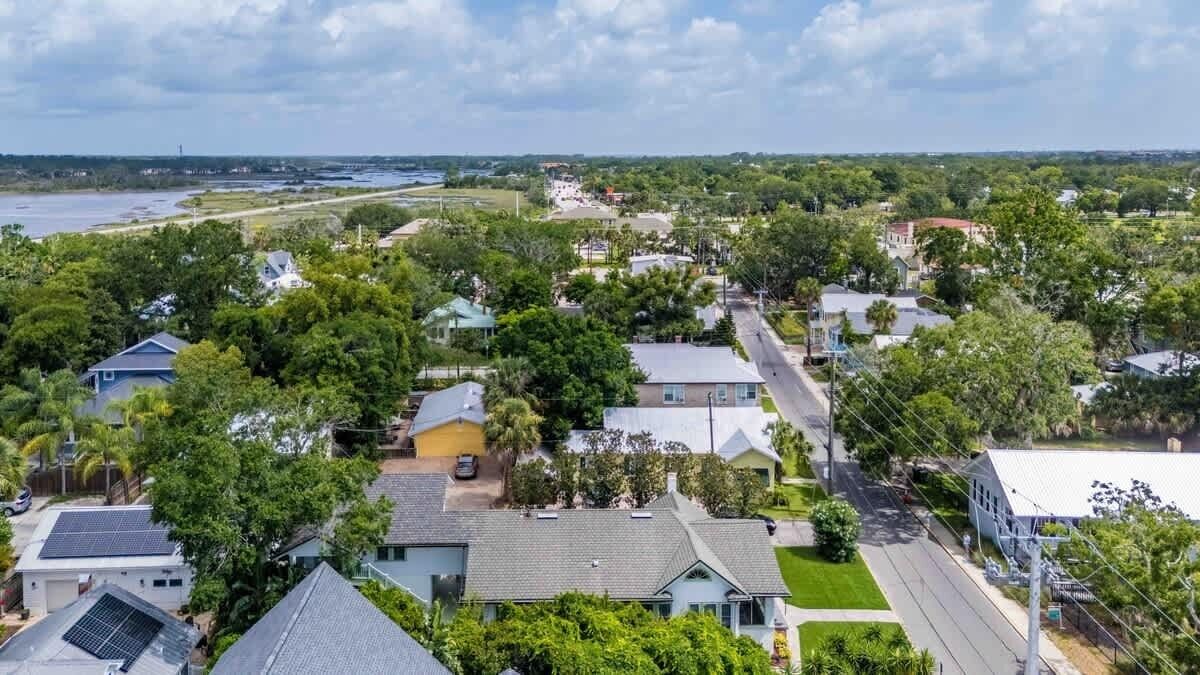 Un quartier résidentiel avec des maisons, une route et une étendue d’eau en arrière-plan.