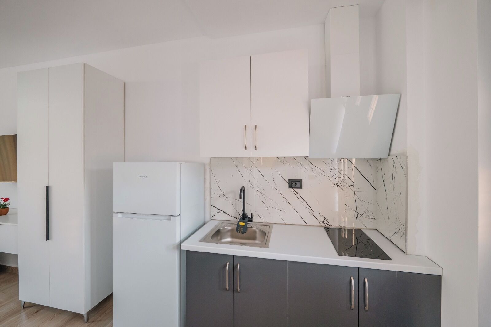 Een moderne keuken met witte kasten, een marmeren spatwand en een inbouwgootsteen.