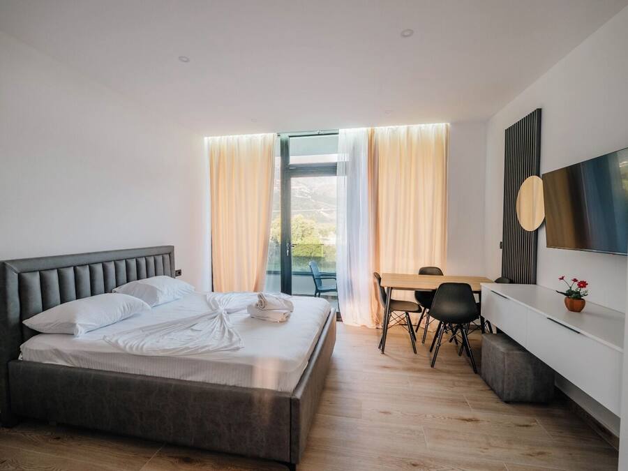 A modern bedroom with a large bed, a desk, and a TV.