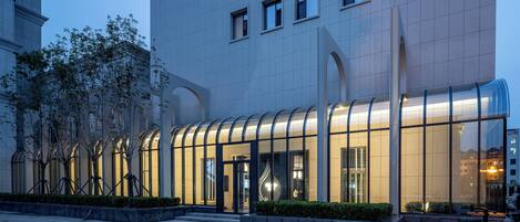 A modern building with a curved glass facade, a well-maintained courtyard with trees, and a clean, tiled ground.