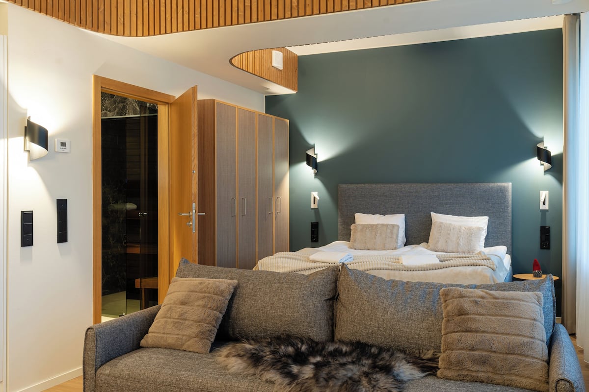 A modern bedroom with a bed, a sofa, and a wardrobe.