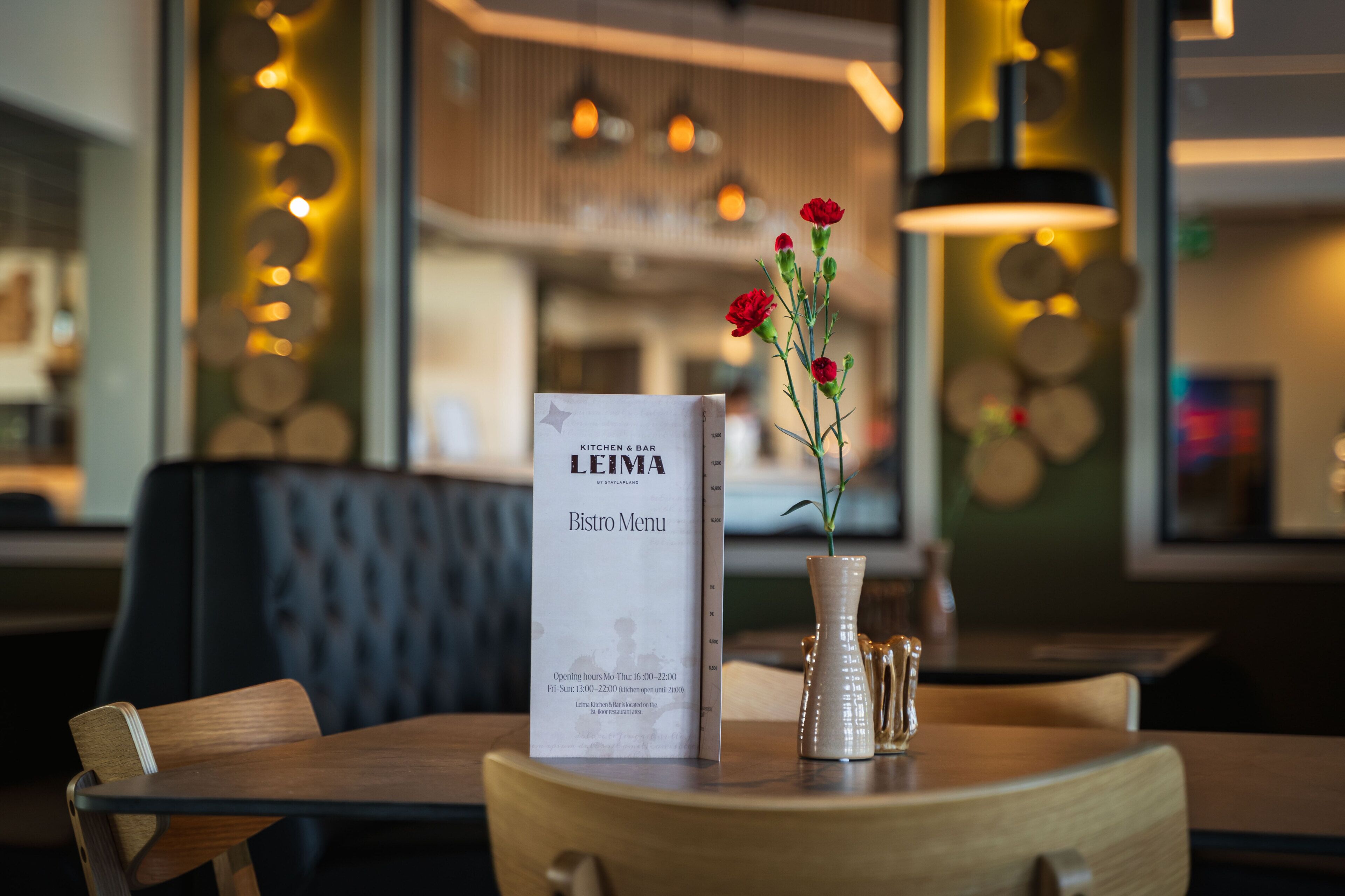 A menu on a table with a vase of flowers.